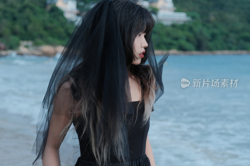 戴黑色头纱站在海边的女人