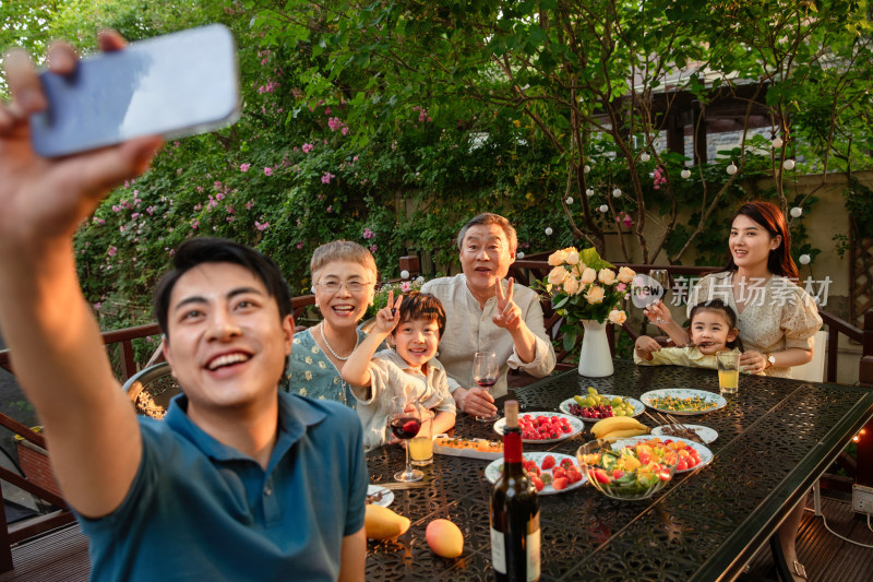 庭院里用餐的大家庭使用手机自拍