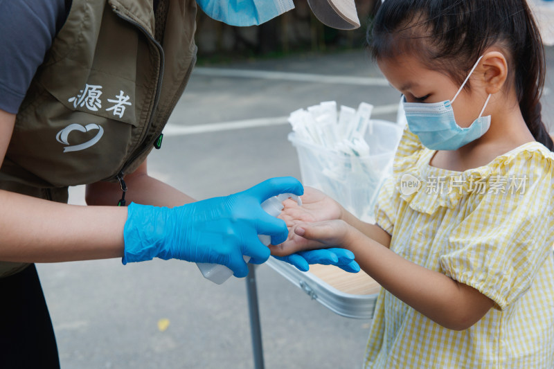 社区志愿者给小女孩用酒精消毒