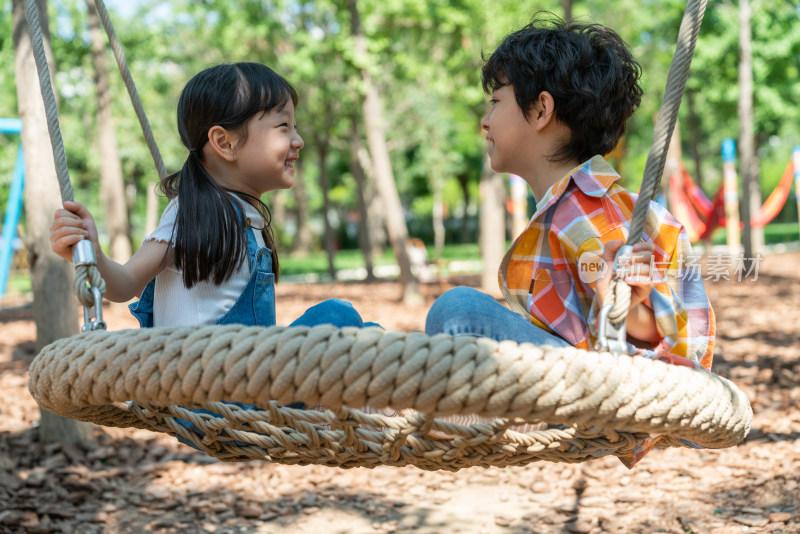 两个小孩子面对面开心荡秋千