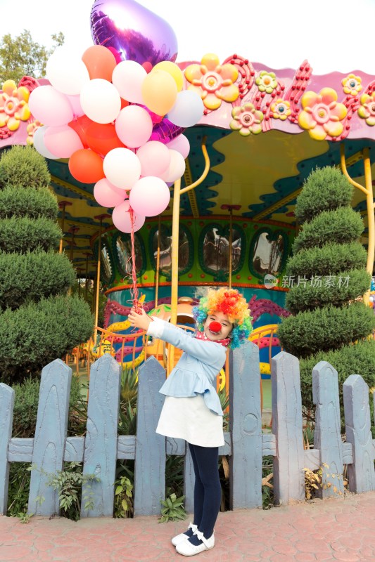 扮小丑的小女孩牵着气球在游乐园