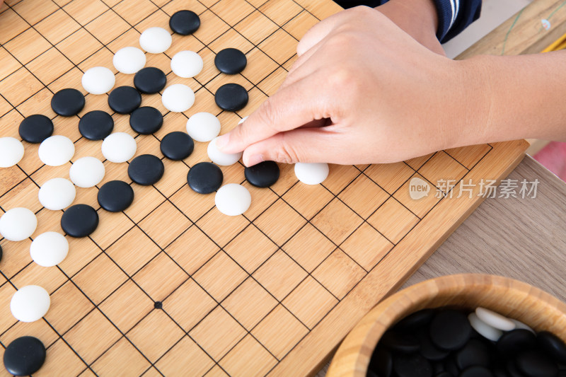 一只大人的手指导着小孩的手下围棋