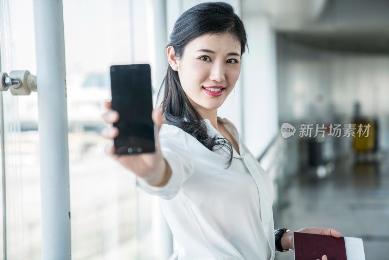 年轻商务女士在机场展示手机