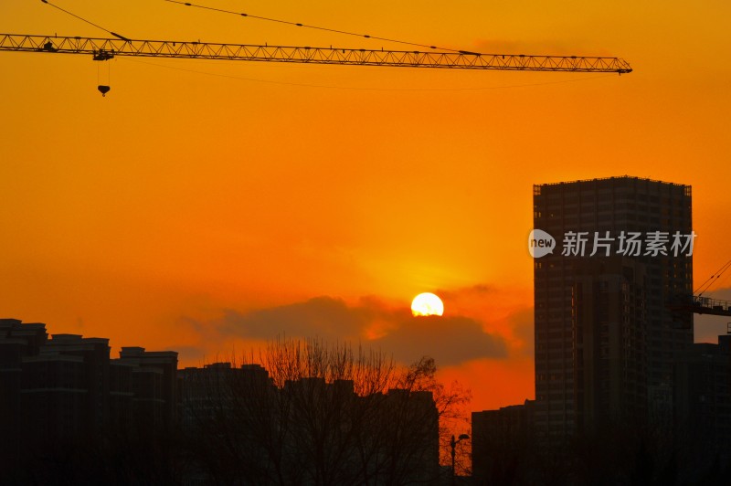 夕阳下带起重机的城市建筑群