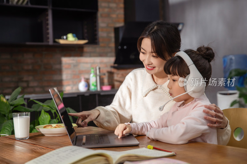 年轻妈妈陪伴孩子在家中上网课
