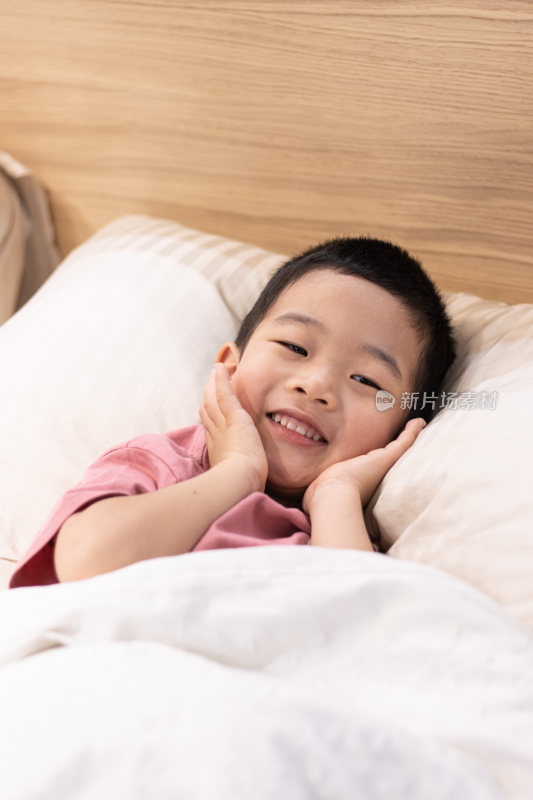 一个小男孩躺在舒适的床上盖着被子
