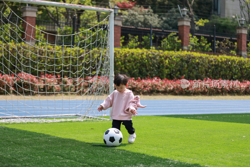 可爱的女孩在足球场上踢球