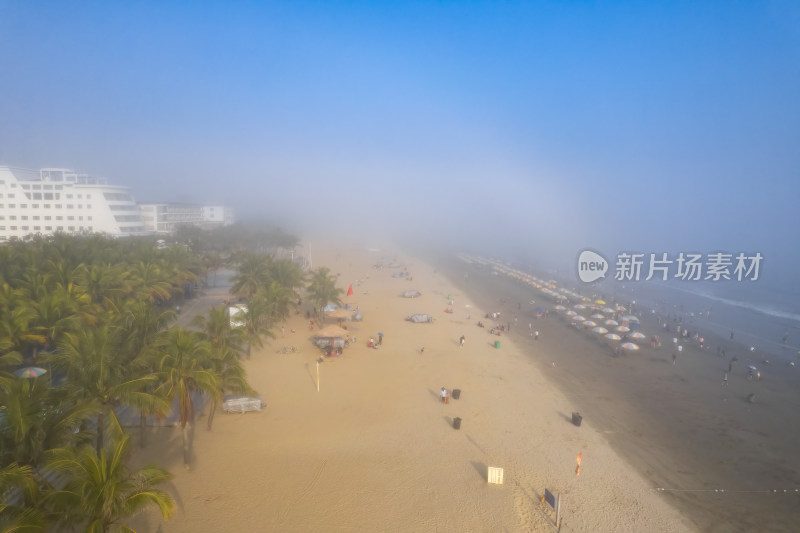 雾中沙滩全景 沙滩上有众多游客和棕榈树