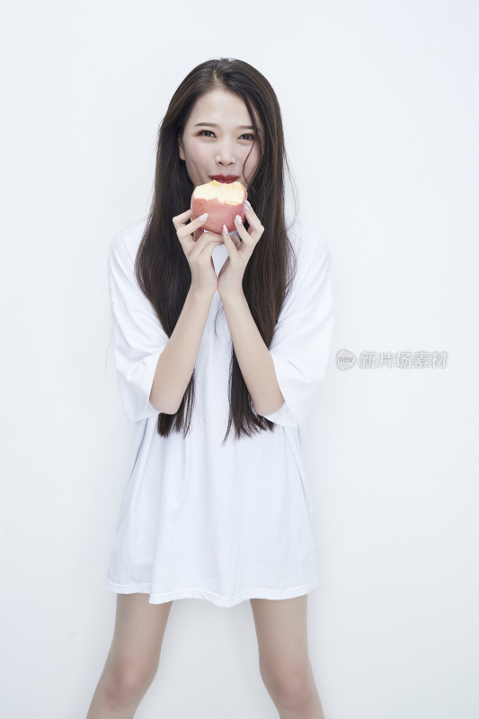 吃苹果的穿白色长T血衫的长发可爱少女人像