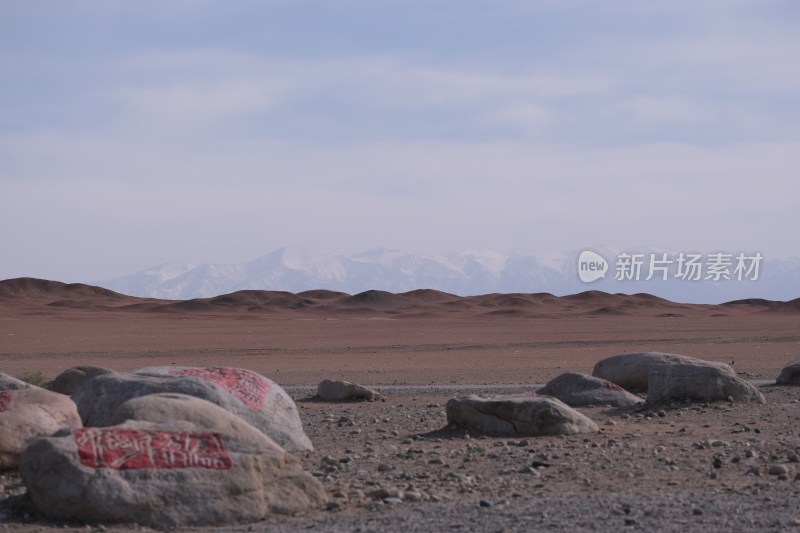 沙漠中带红字的石头与雪山远景