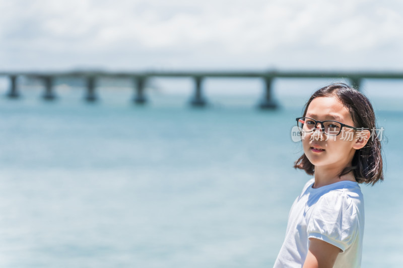 小女孩在海边眺望远处的跨海大桥