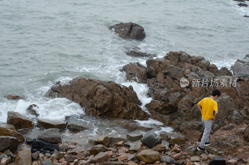 青岛海边海岛上一个穿黄色衬衫的男子