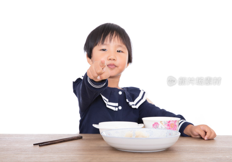 餐桌上吃过饭的小女孩用手指着镜头