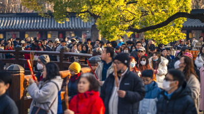 古建筑前人群聚集手持香祈福场景