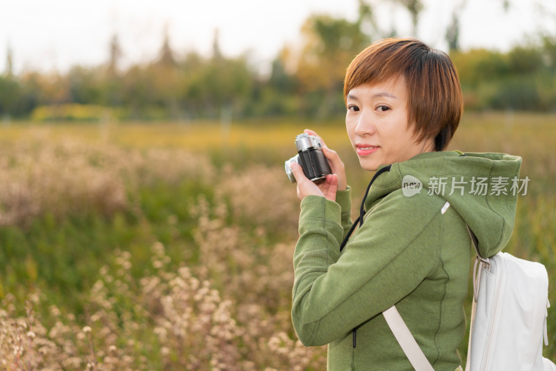 站在花丛中摄影的中国籍女性