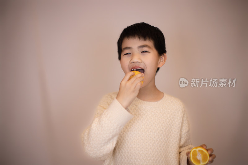 一个帅气的中国小男孩在吃橙子