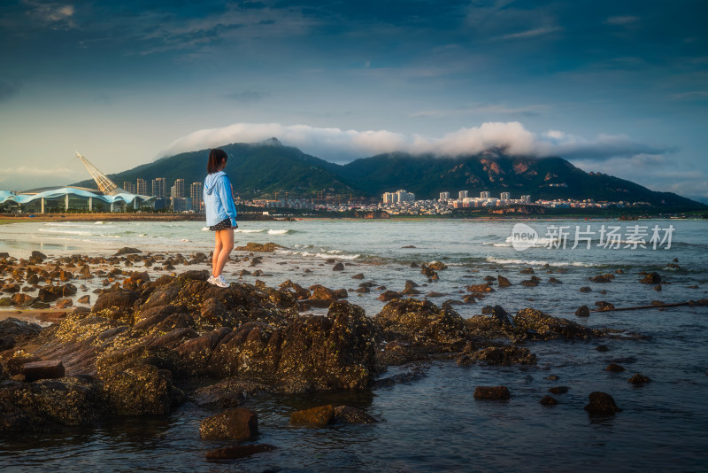 女孩站在海边礁石眺望远方