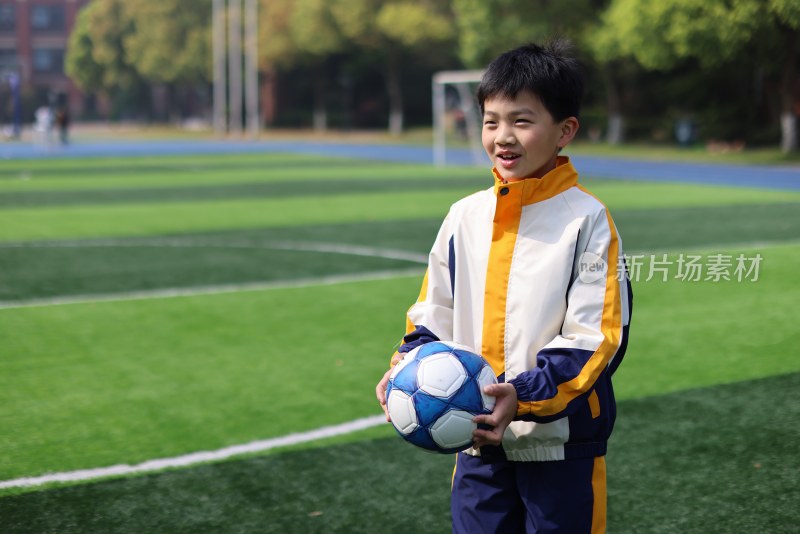 男孩在足球场上拿着足球的肖像