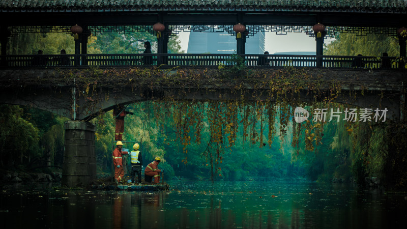 工人于古桥下河道作业场景