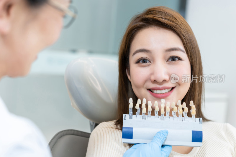 医生给患者在牙科诊所匹配牙齿