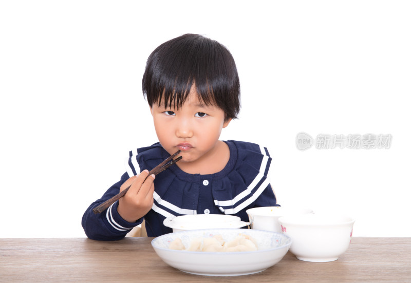 白背景前的黄皮肤小女孩吃着饭时看向镜头