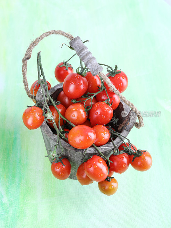 绿色背景上，篮子中的新鲜水果西红柿番茄