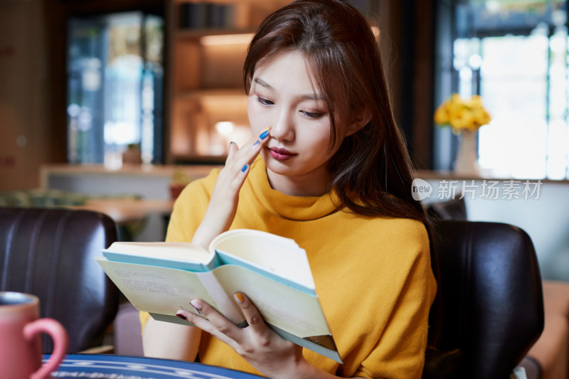 在图书咖啡馆阅读书籍的少女