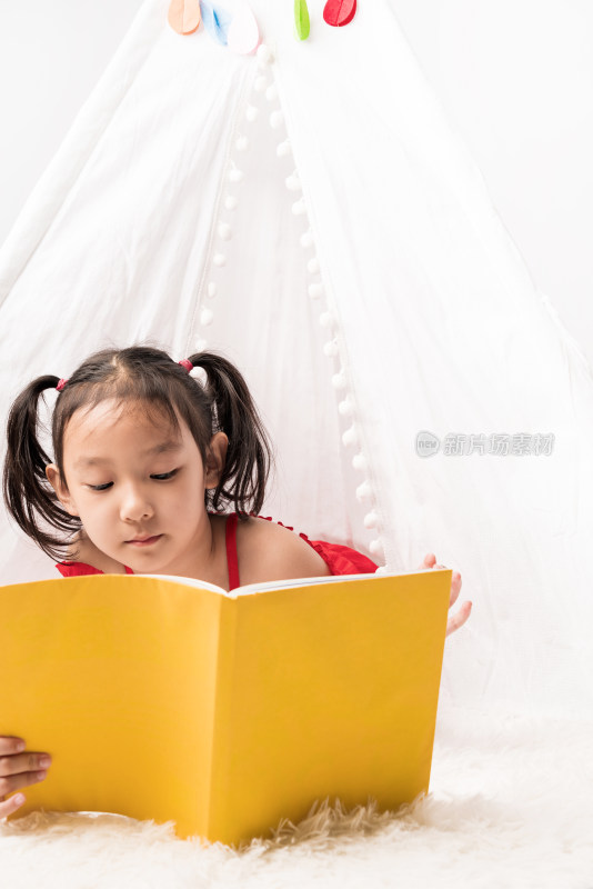 趴在白色帐篷里认真读书的中国女孩