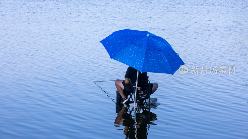 河边打着遮阳伞的男子钓鱼身影