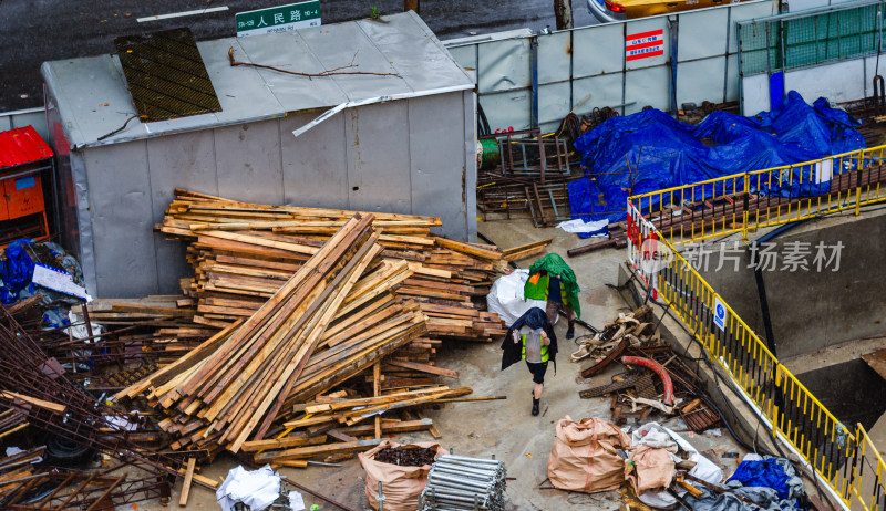 城市雨中工地里堆积的建筑材料和避雨的工人