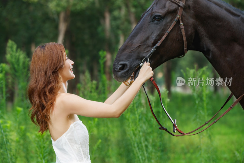 草丛中漂亮的青年女人牵着马