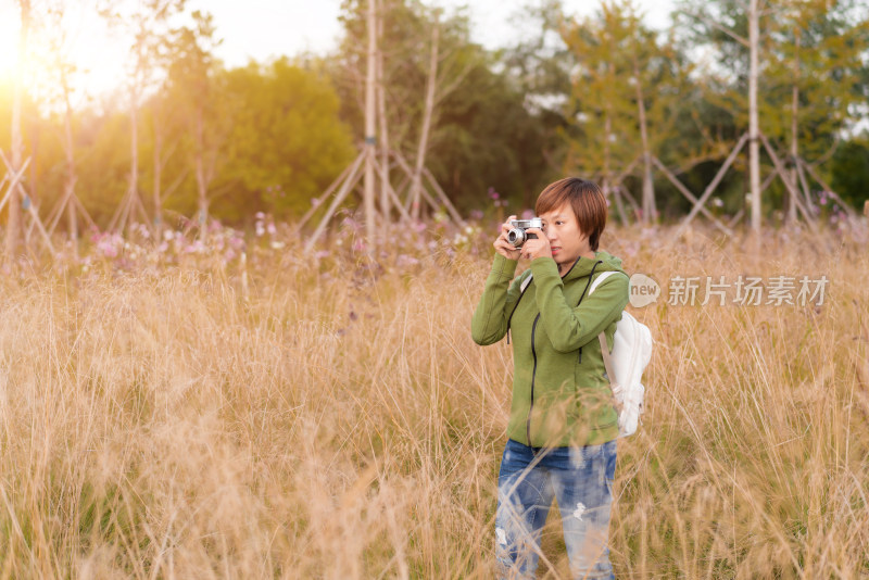 站在干枯草丛中拍照的中国籍女性