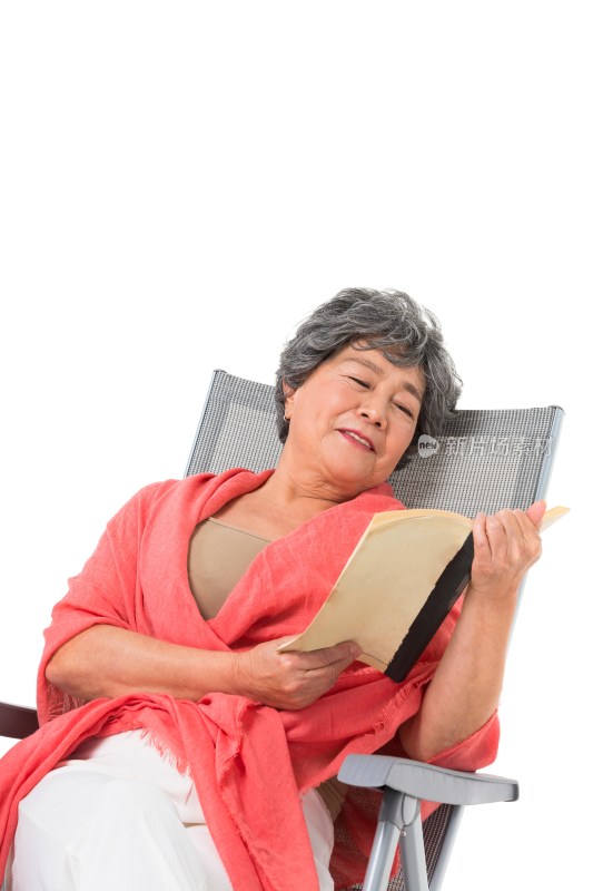 中老年女人坐在沙滩椅上看书