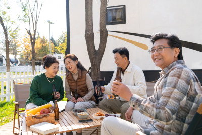 一群中老年人坐在房车露营地喝啤酒聊天