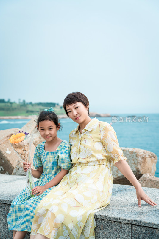 夏天坐在海边玩耍的中国母女