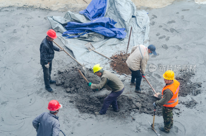 建筑工地上几个合作挖坑的建筑工人