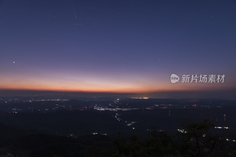 城市上空夜晚彗星落下山间风车群的壮观景象