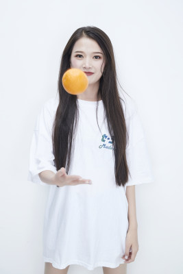 玩耍橙子穿白色长T血的亚洲可爱少女人像