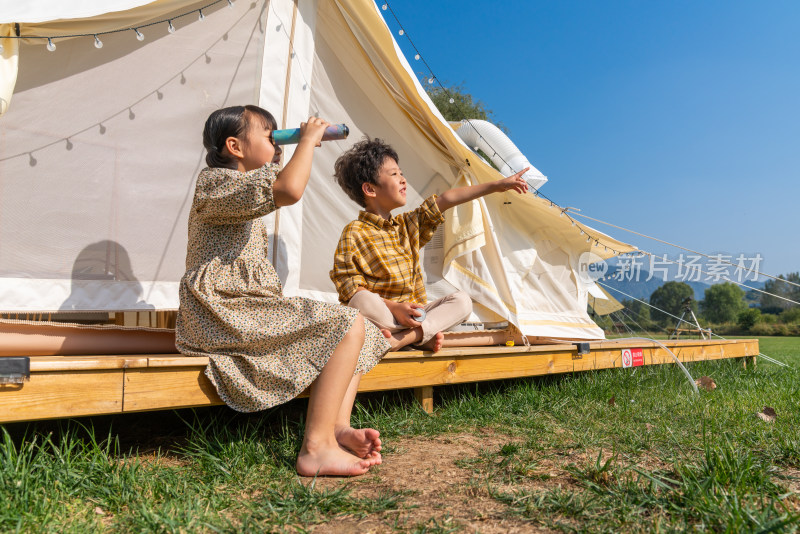 两个孩子坐在帐篷外玩耍
