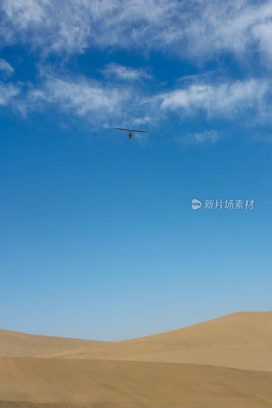 蓝天白云滑翔机从沙丘上飞过