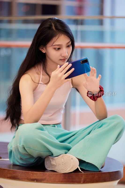 假日在商场休息区用手机自拍的中国少女