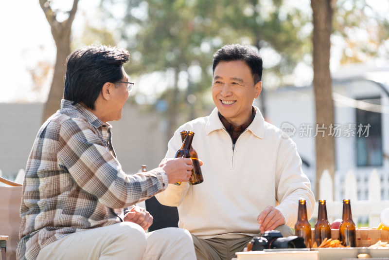 两个老年男人坐在露营地喝啤酒