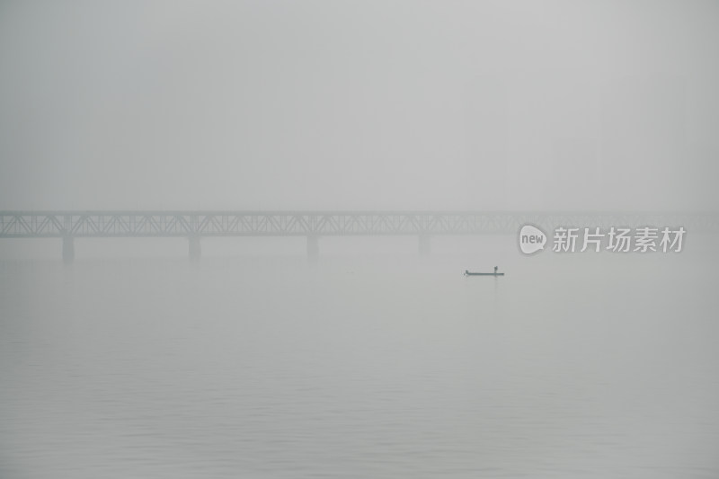浙江杭州雾中钱塘江大桥与江面的小船人影