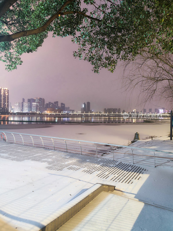 江边雪景城市夜景灯光映照下的江景