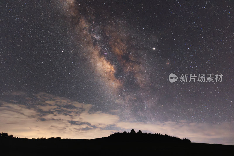 夜空下的璀璨星河与地面树林剪影