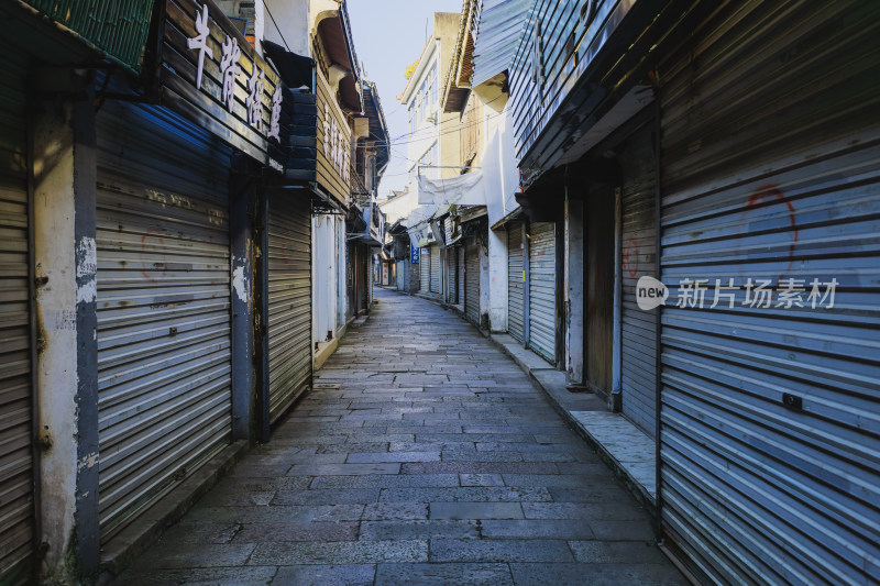 狭长小巷两侧布满卷帘门的冷清街景