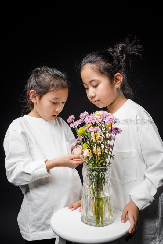 两个在黑背景前插花的亚裔女孩