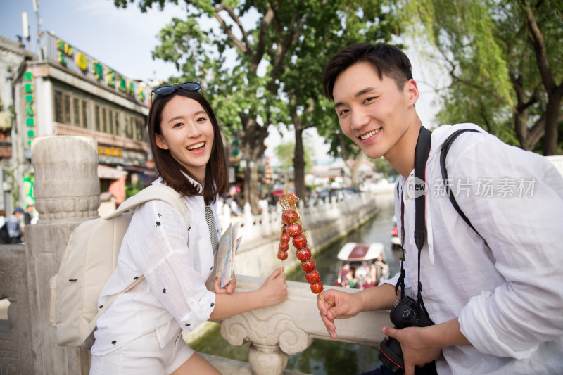 青年情侣旅游拿着糖葫芦