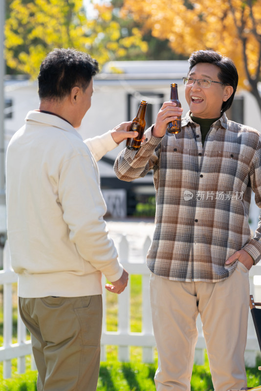 两个老年男人站在露营地喝啤酒