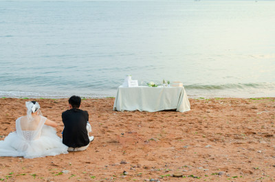 海边婚纱情侣坐沙滩观景